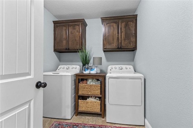 laundry area with cabinet space, separate washer and dryer, baseboards, and a textured ceiling