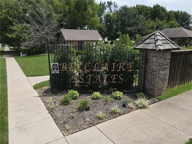 community / neighborhood sign featuring a yard and fence