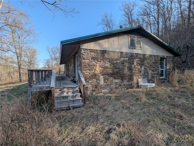 view of side of property with a wooden deck and stone siding