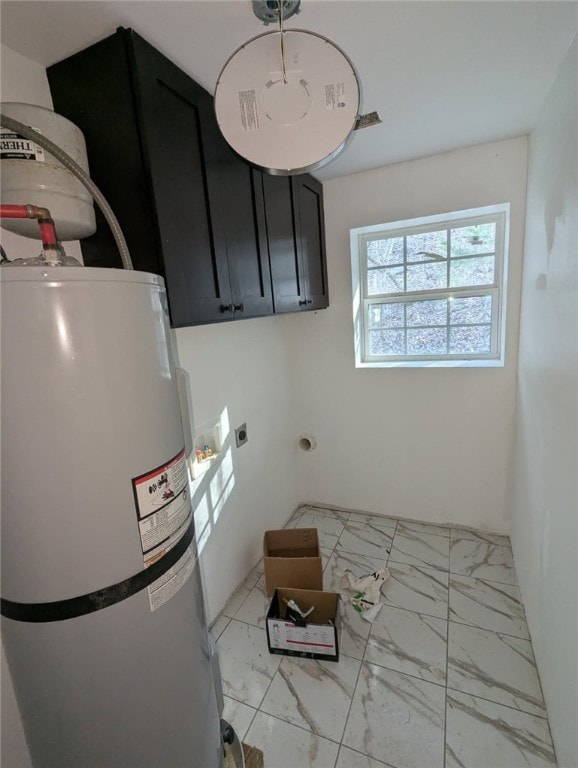 clothes washing area featuring electric dryer hookup, cabinet space, marble finish floor, and electric water heater