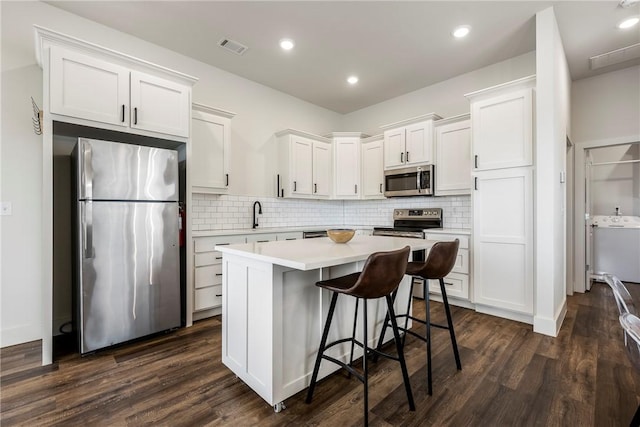 kitchen featuring white cabinets, a center island, dark wood-style flooring, and stainless steel appliances