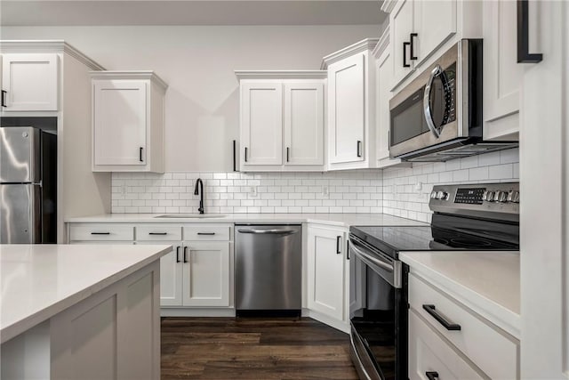 kitchen with dark wood finished floors, a sink, decorative backsplash, light countertops, and stainless steel appliances