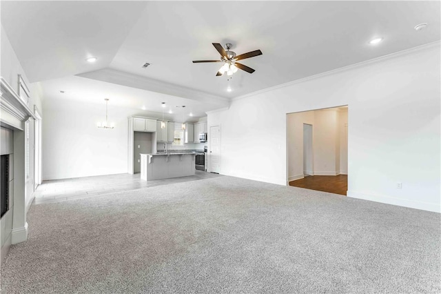 unfurnished living room with light carpet, recessed lighting, ceiling fan with notable chandelier, and ornamental molding