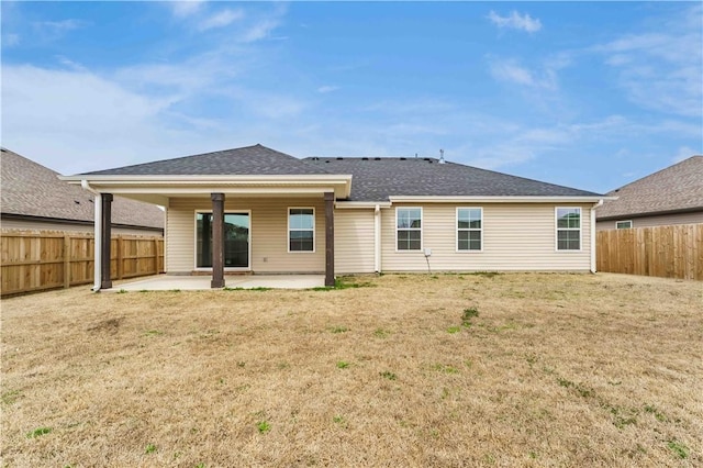 rear view of house with a yard, a shingled roof, a fenced backyard, and a patio area