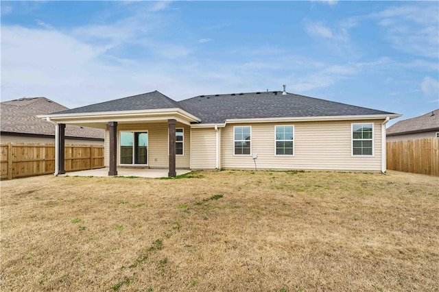 rear view of property with a yard, a patio area, a fenced backyard, and roof with shingles