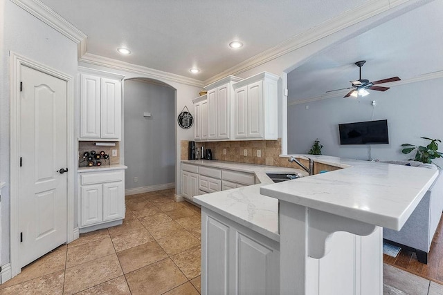 kitchen with a peninsula, white cabinetry, a ceiling fan, and a sink