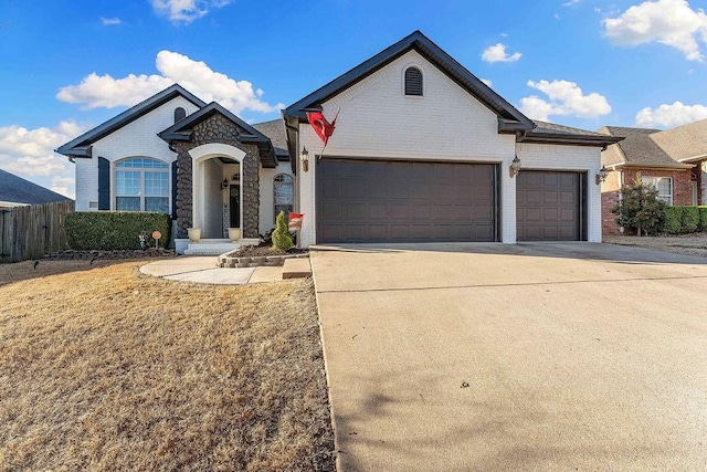 view of front of home featuring brick siding, an attached garage, concrete driveway, and fence