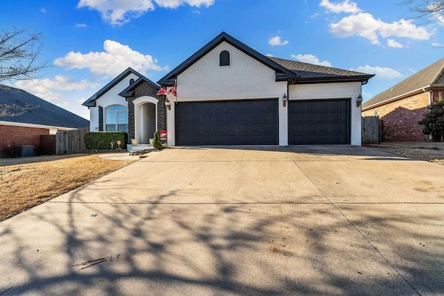 view of front facade featuring brick siding, concrete driveway, an attached garage, and fence