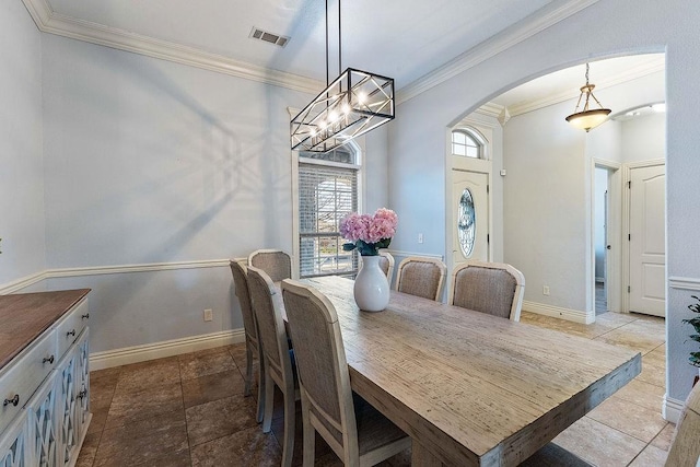 dining room with crown molding, baseboards, arched walkways, and visible vents