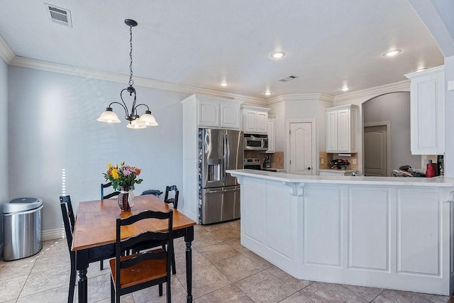 kitchen featuring white cabinetry, arched walkways, appliances with stainless steel finishes, light countertops, and a chandelier