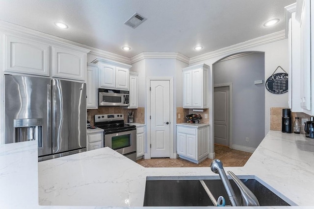 kitchen featuring visible vents, a sink, tasteful backsplash, stainless steel appliances, and white cabinets