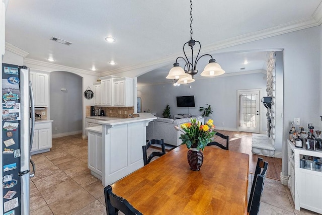 dining area with visible vents, crown molding, baseboards, a chandelier, and arched walkways