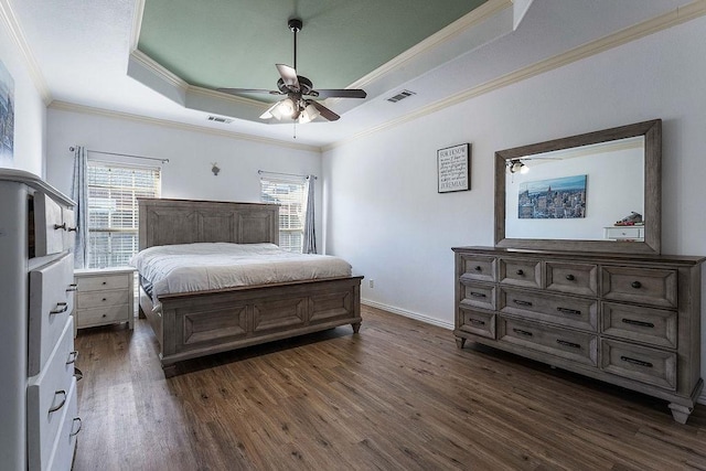 bedroom with visible vents, baseboards, dark wood-type flooring, and a tray ceiling