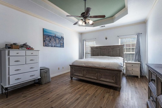 bedroom with visible vents, crown molding, baseboards, dark wood finished floors, and a raised ceiling