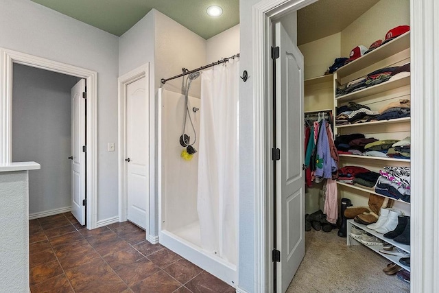 full bathroom with a walk in closet and a stall shower