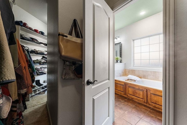 bathroom featuring a bath, tile patterned floors, and a walk in closet