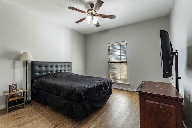 bedroom featuring baseboards, light wood finished floors, and ceiling fan