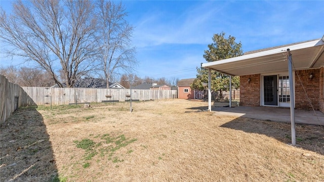 view of yard with an outbuilding, a storage unit, a fenced backyard, and a patio