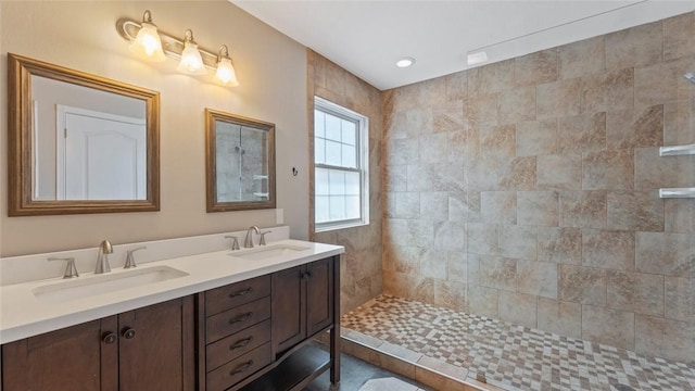 full bathroom with a sink, tiled shower, and double vanity