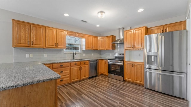 kitchen with visible vents, a sink, stainless steel appliances, wall chimney exhaust hood, and dark wood-style flooring