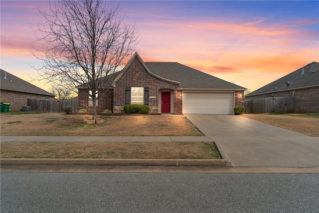 view of front facade with brick siding, fence, cooling unit, driveway, and an attached garage