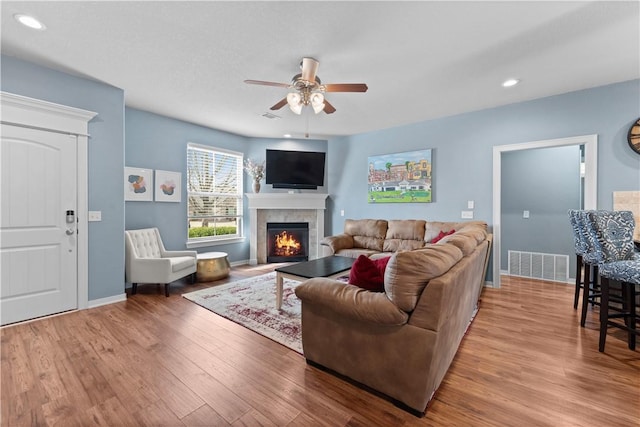 living area featuring visible vents, a ceiling fan, wood finished floors, recessed lighting, and a fireplace