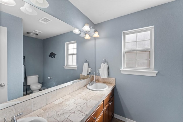 full bath with a sink, visible vents, toilet, and double vanity