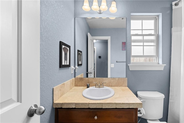 bathroom featuring a chandelier, toilet, and vanity