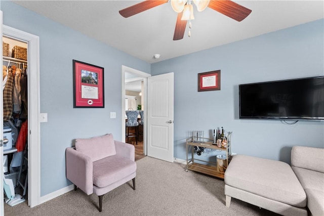 sitting room with baseboards, carpet floors, and ceiling fan