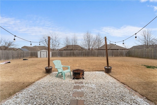 view of yard with an outbuilding, a fenced backyard, a shed, and an outdoor fire pit