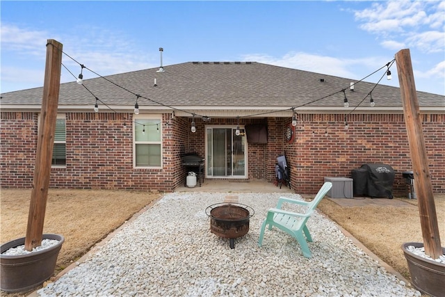 back of house featuring brick siding, a patio area, an outdoor fire pit, and roof with shingles