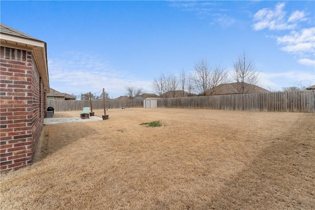 view of yard with a patio, an outbuilding, a fenced backyard, a fire pit, and a storage shed