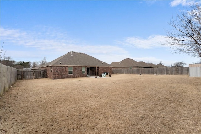 rear view of house featuring a patio, brick siding, and a fenced backyard