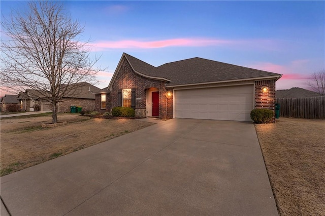 view of front of home featuring concrete driveway, an attached garage, brick siding, and roof with shingles