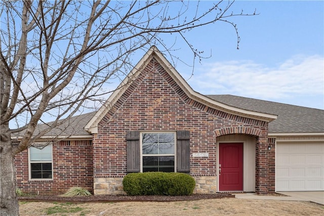 view of front of property with brick siding, an attached garage, and roof with shingles