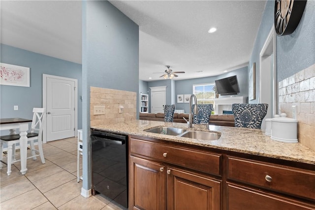 kitchen featuring light stone countertops, black dishwasher, decorative backsplash, light tile patterned flooring, and a sink