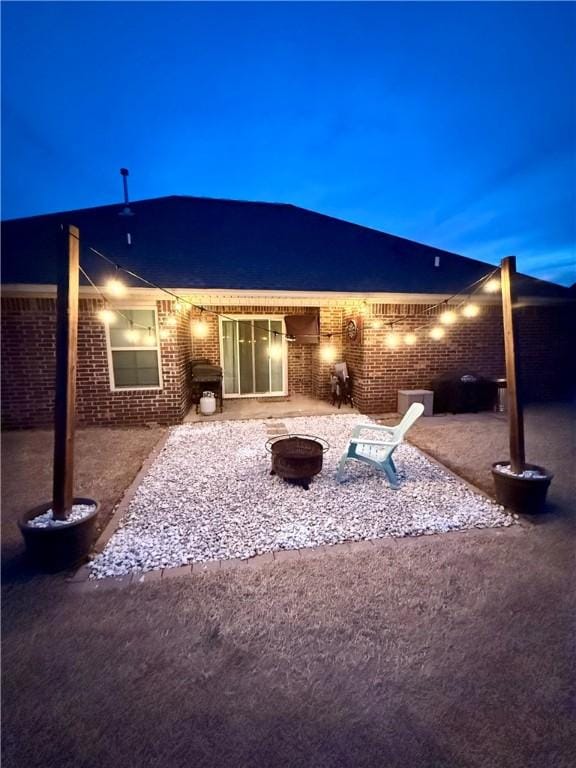 back of property featuring a patio, brick siding, and an outdoor fire pit