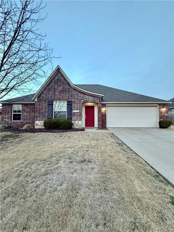 ranch-style house with brick siding, an attached garage, concrete driveway, and a front yard