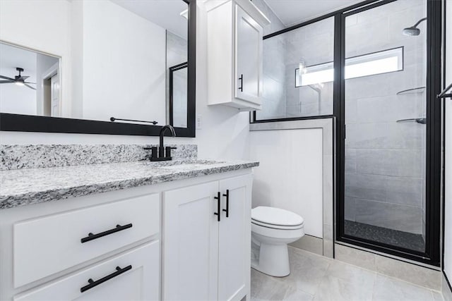 bathroom featuring a shower stall, toilet, vanity, and ceiling fan