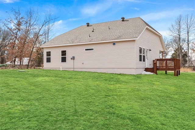 rear view of house with a yard, a deck, and a shingled roof