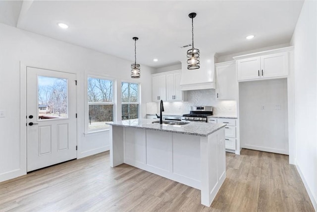 kitchen featuring white cabinets, gas stove, tasteful backsplash, and a sink