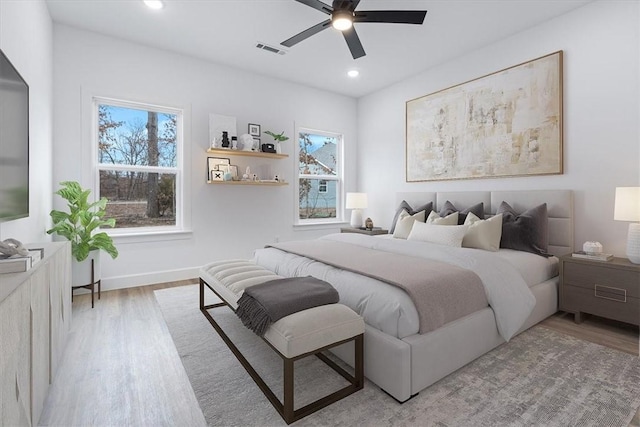 bedroom featuring visible vents, multiple windows, and light wood-style floors