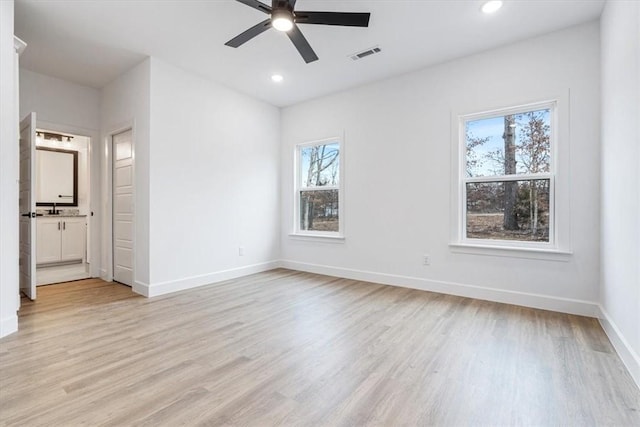 empty room with a ceiling fan, visible vents, light wood finished floors, baseboards, and recessed lighting