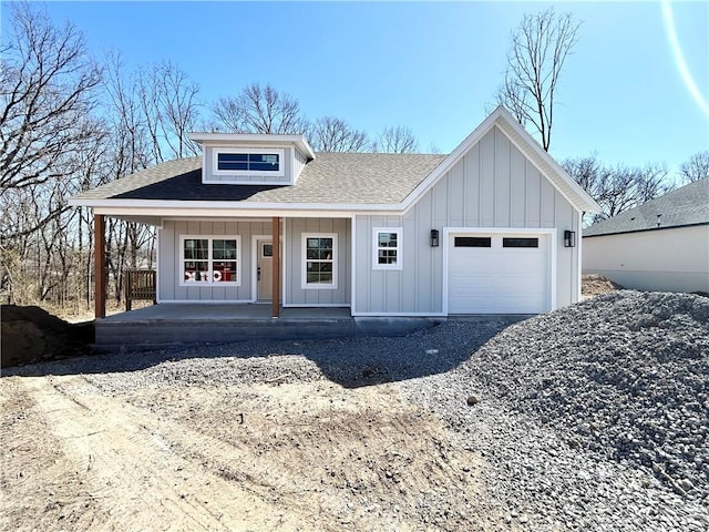 view of front of house with covered porch, board and batten siding, an attached garage, and roof with shingles