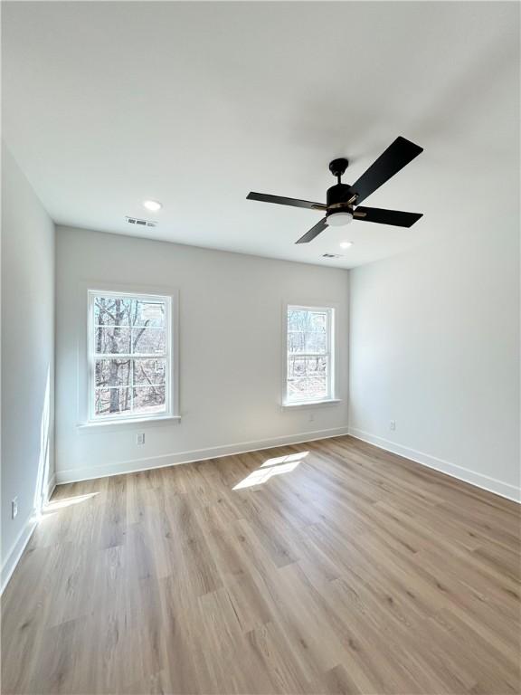 unfurnished room featuring ceiling fan, light wood-style floors, visible vents, and baseboards