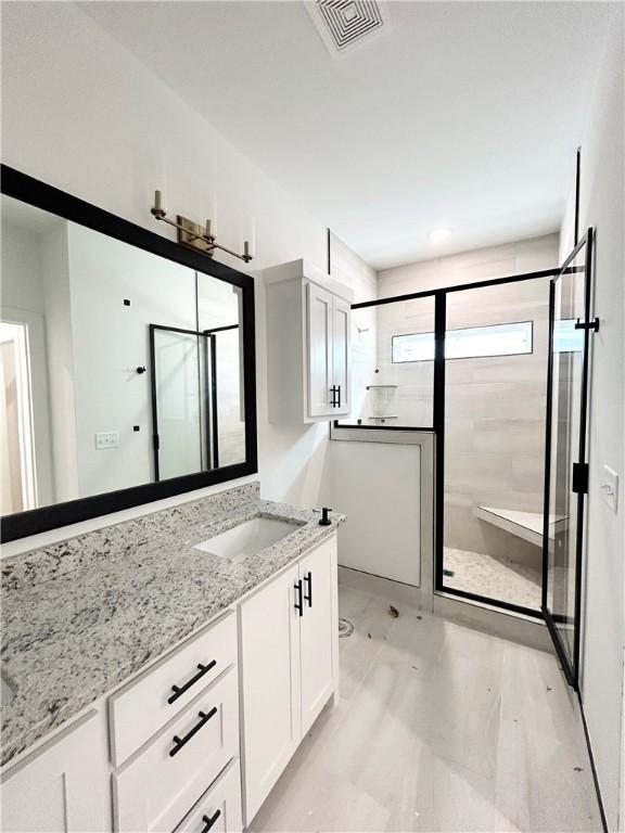 bathroom with visible vents, a shower stall, and vanity