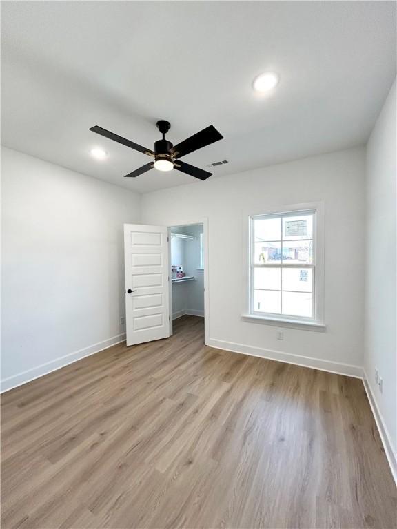 empty room with a ceiling fan, baseboards, and wood finished floors