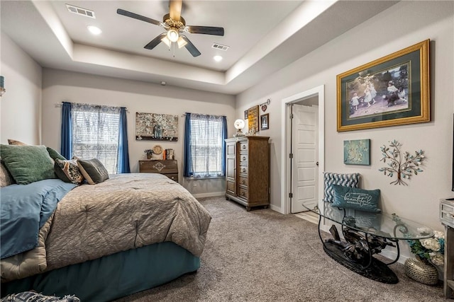 bedroom with visible vents, baseboards, a tray ceiling, and carpet floors