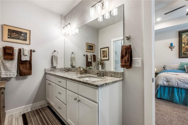 bathroom with a sink, connected bathroom, baseboards, and double vanity