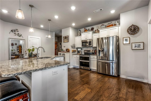 kitchen featuring visible vents, a sink, appliances with stainless steel finishes, white cabinetry, and dark wood-style flooring